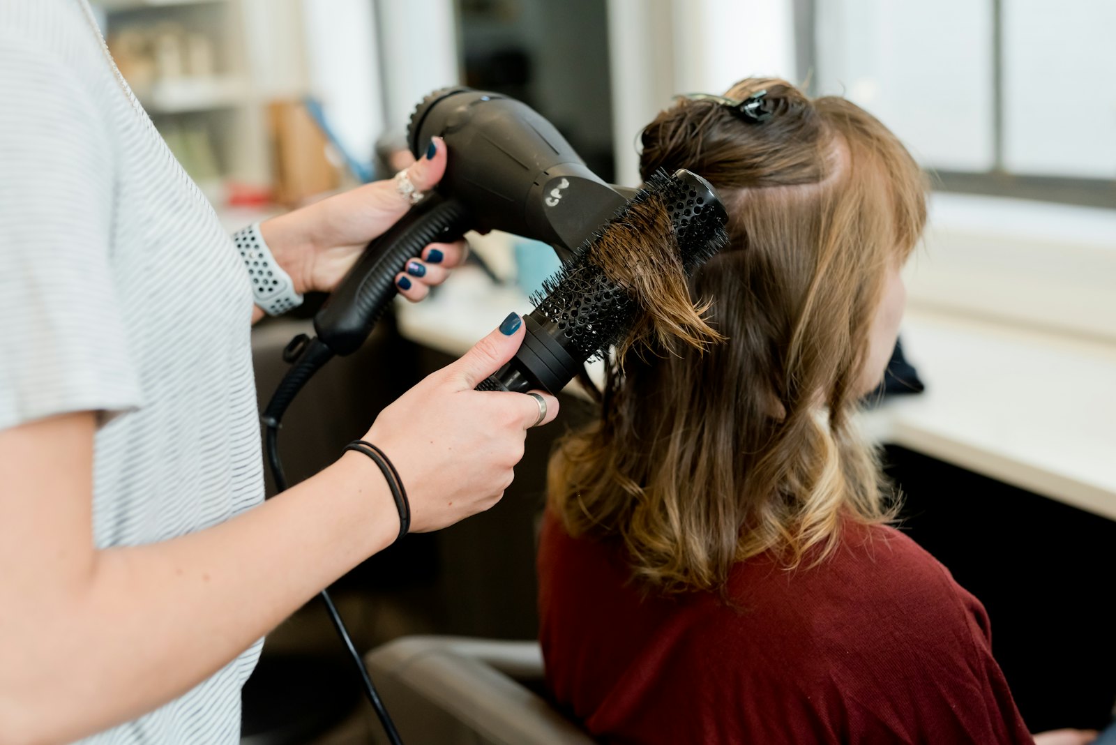 Estilista secando el pelo a una clienta